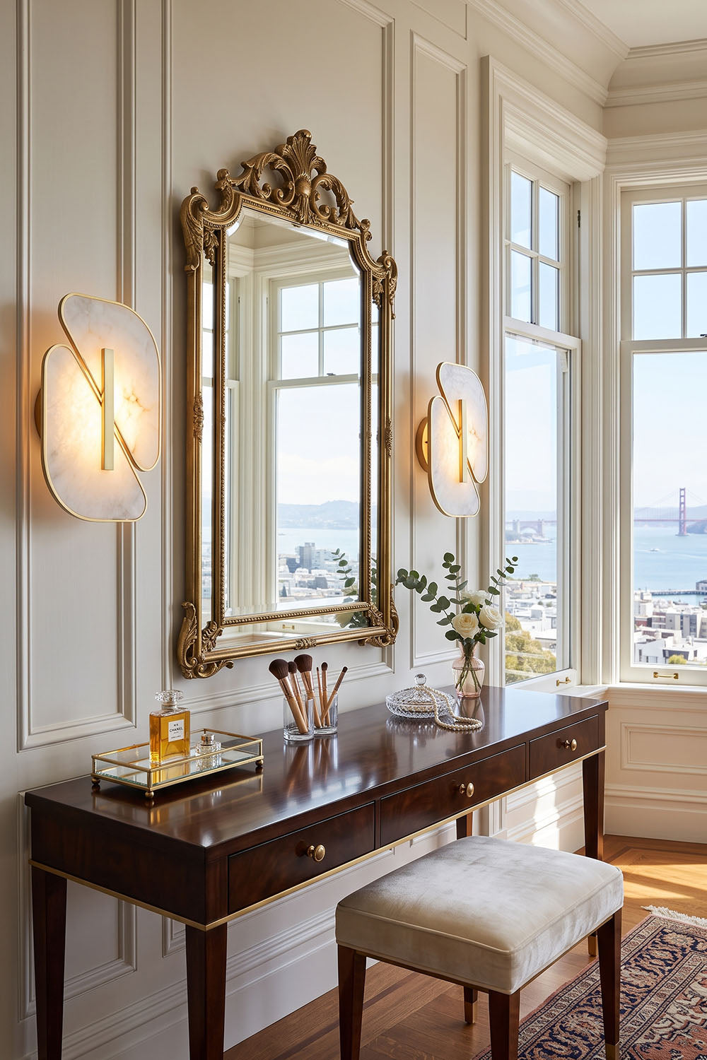 Nerine Overlapping Alabaster Wall Lamp illuminating elegant vanity with gold-framed mirror and scenic bay view.