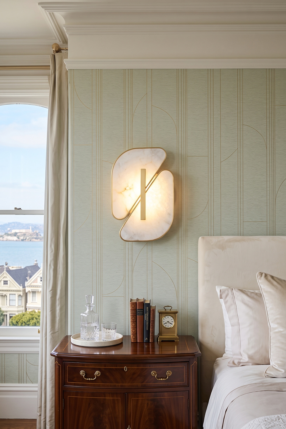 Nerine Overlapping Alabaster Wall Lamp illuminating a stylish bedroom with elegant decor.