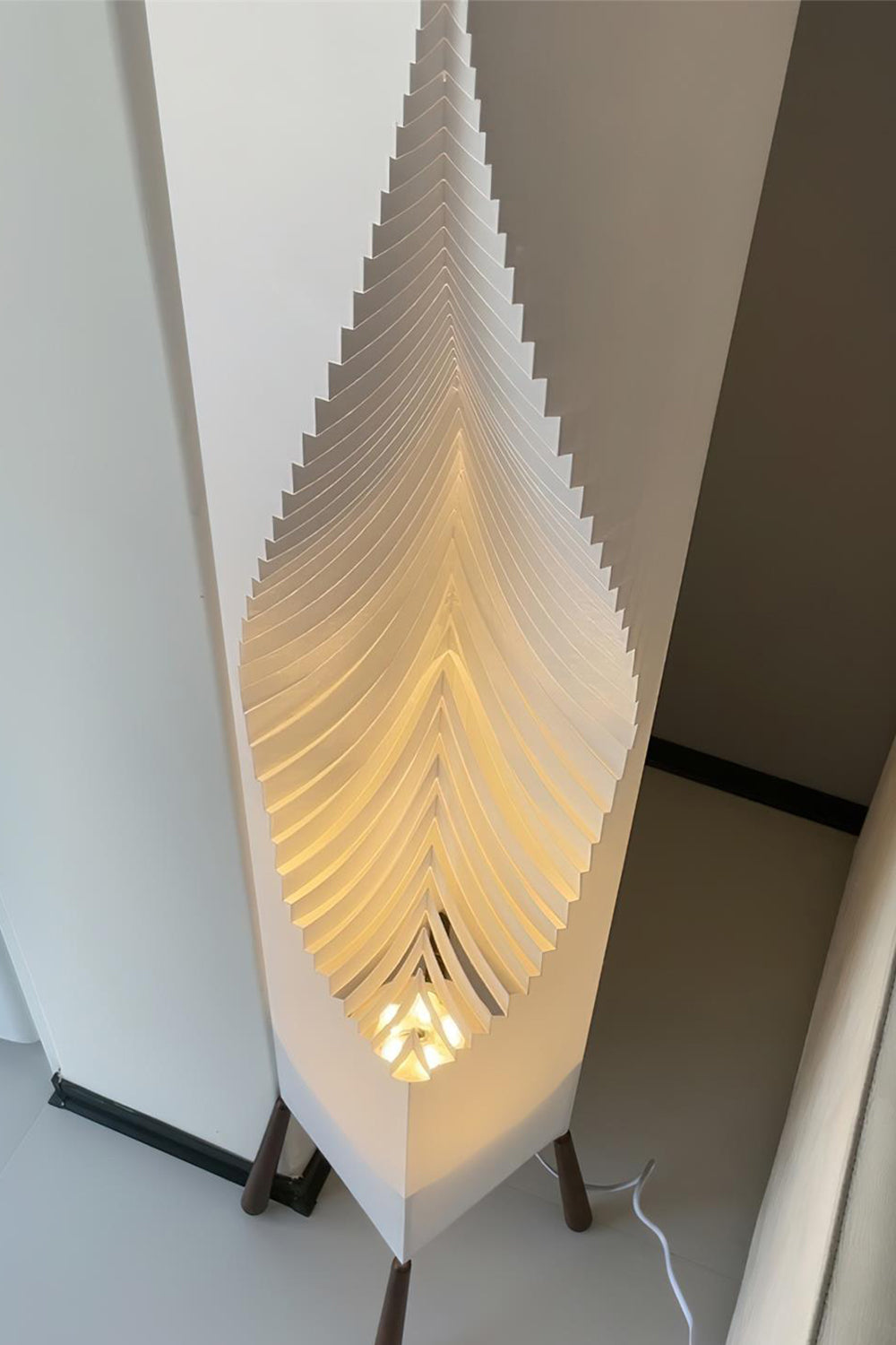 Nori Sculptural Leaf Floor Lamp | Fabric, Wood | Close-up side profile view of the glowing ribbed geometric folds of the sculptural white fabric shade | Detail shot | Samu Lamp