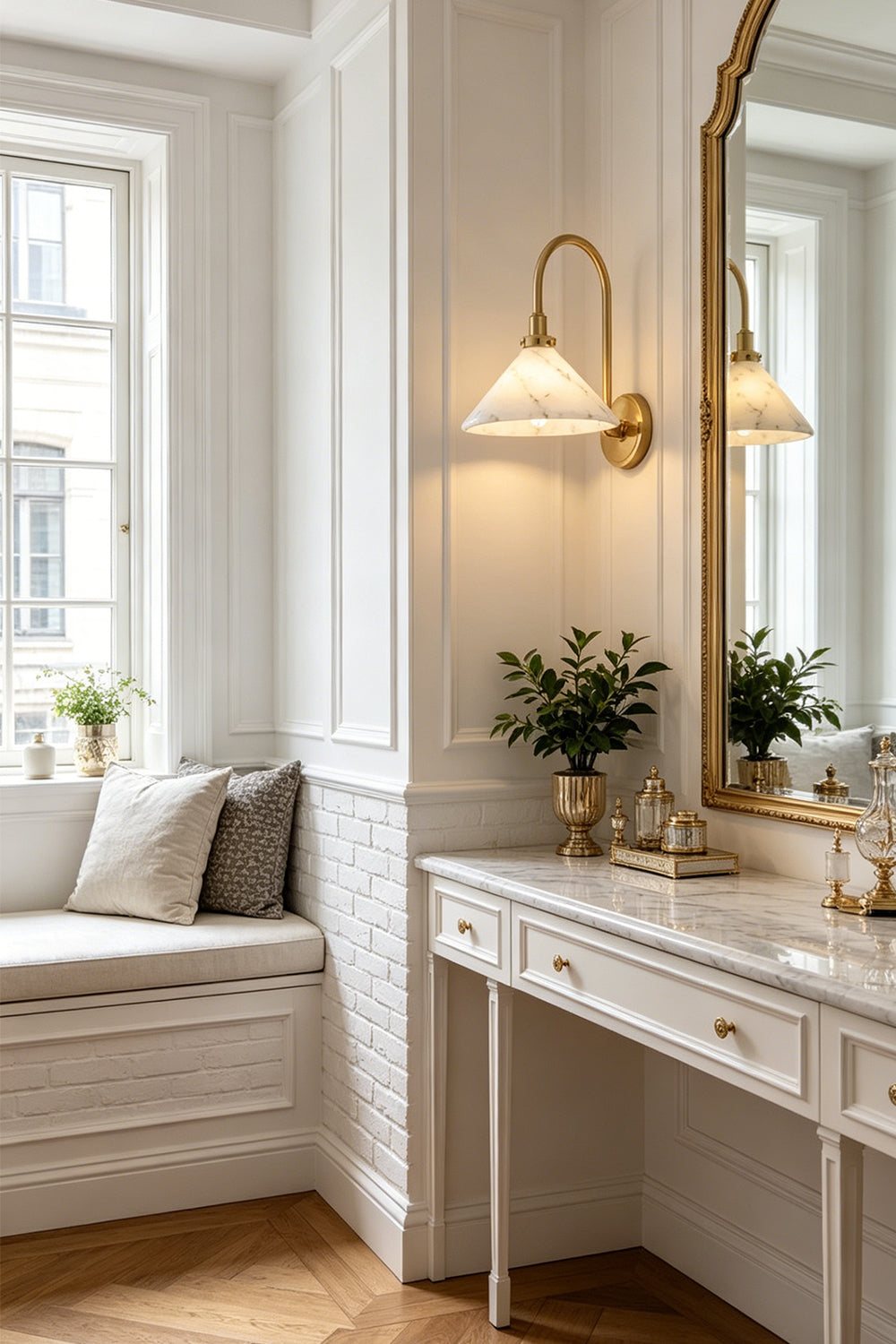 Odette Alabaster Curved Wall Sconce | Vanity Lighting | Installed on a white wall as a stylish vanity sconce next to a tall gold-trimmed mirror and a pristine white dressing table setup | Samu Lamp