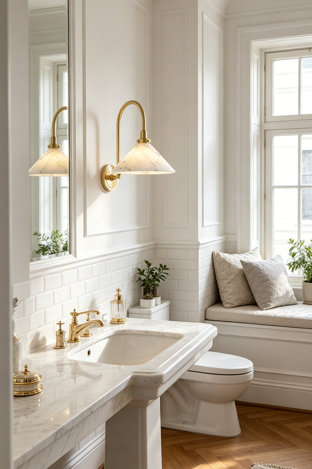 Odette Alabaster Curved Wall Sconce | Bathroom Sconce | Mounted in a luxury white residential bathroom next to a marble sink countertop, large mirror, and sunlit window bench | Samu Lamp
