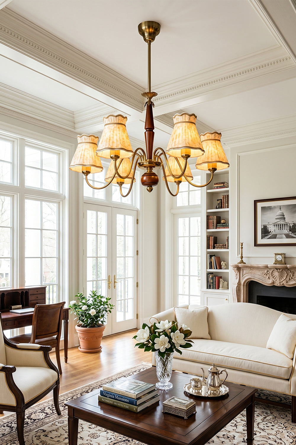 Odette Vintage Pleated Shaded Chandelier | Wood, Brass, Fabric | Hanging as an elegant classical centerpiece in a bright European-style living room featuring white grid windows, a cream sofa, and a fireplace | Samu Lamp