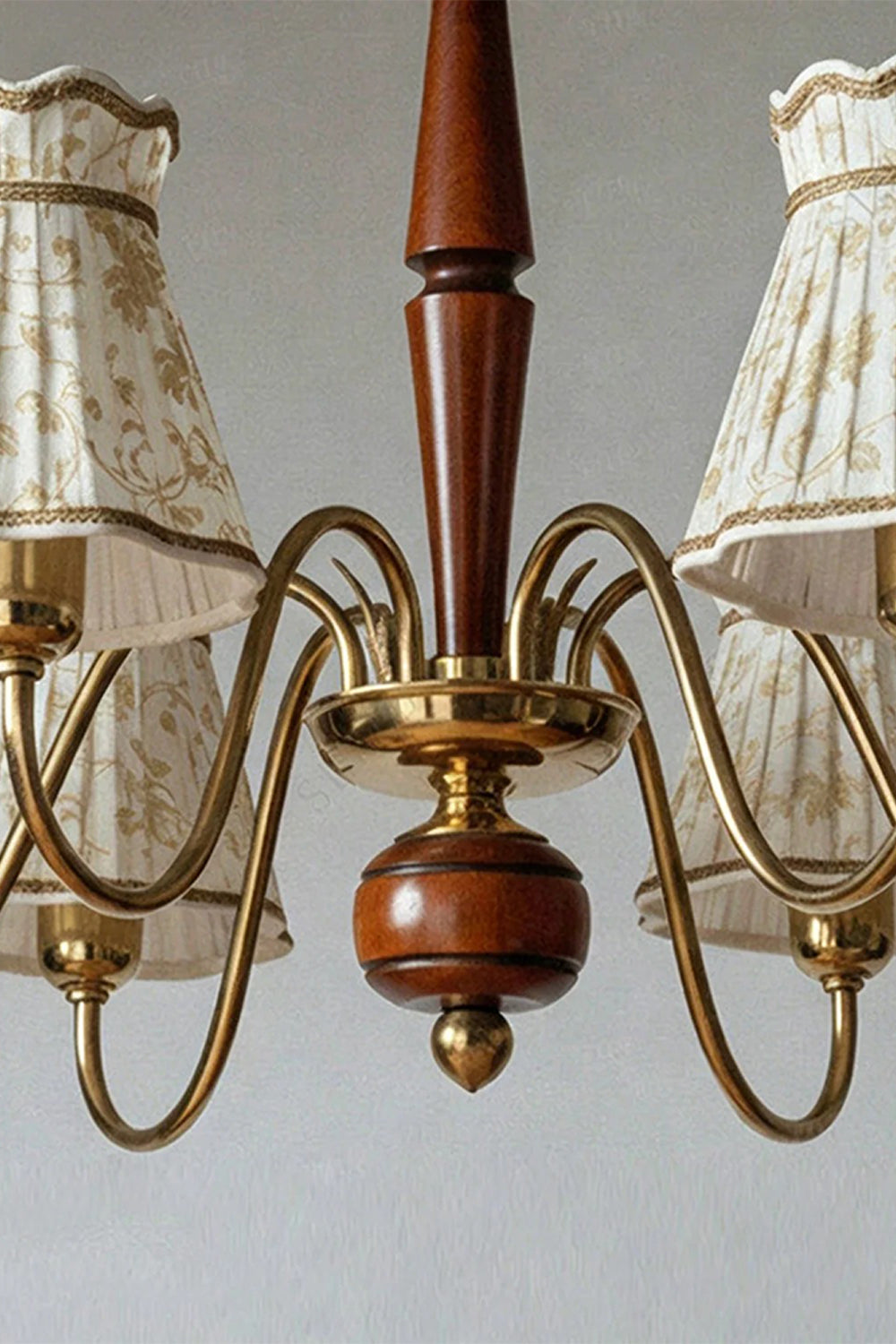 Odette Vintage Pleated Shaded Chandelier | Wood, Brass, Fabric | Close-up structural detail shot focusing on the turned wood central spindle and the ornate twisted brass scroll arm connections | Detail shot | Samu Lamp