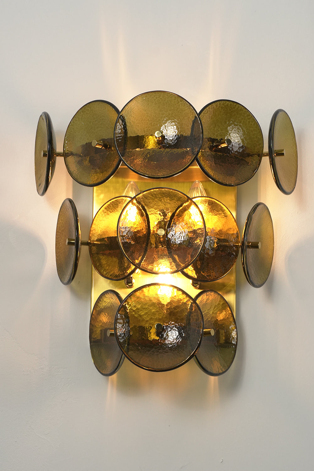 Lit tiered olive green hammered glass wall light | Metal, Glass | Angled lit product view showing tiered layers | Samu Lamp