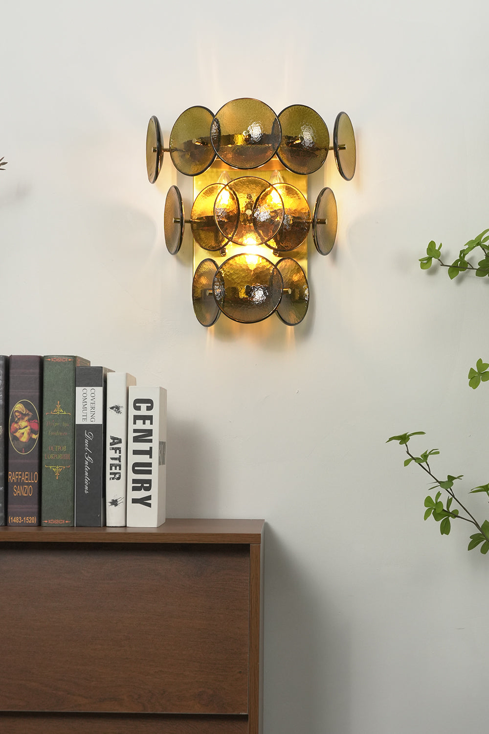 Lit olive green hammered glass wall lamp | Metal, Glass | Installed in a corner near a plant and books | Samu Lamp