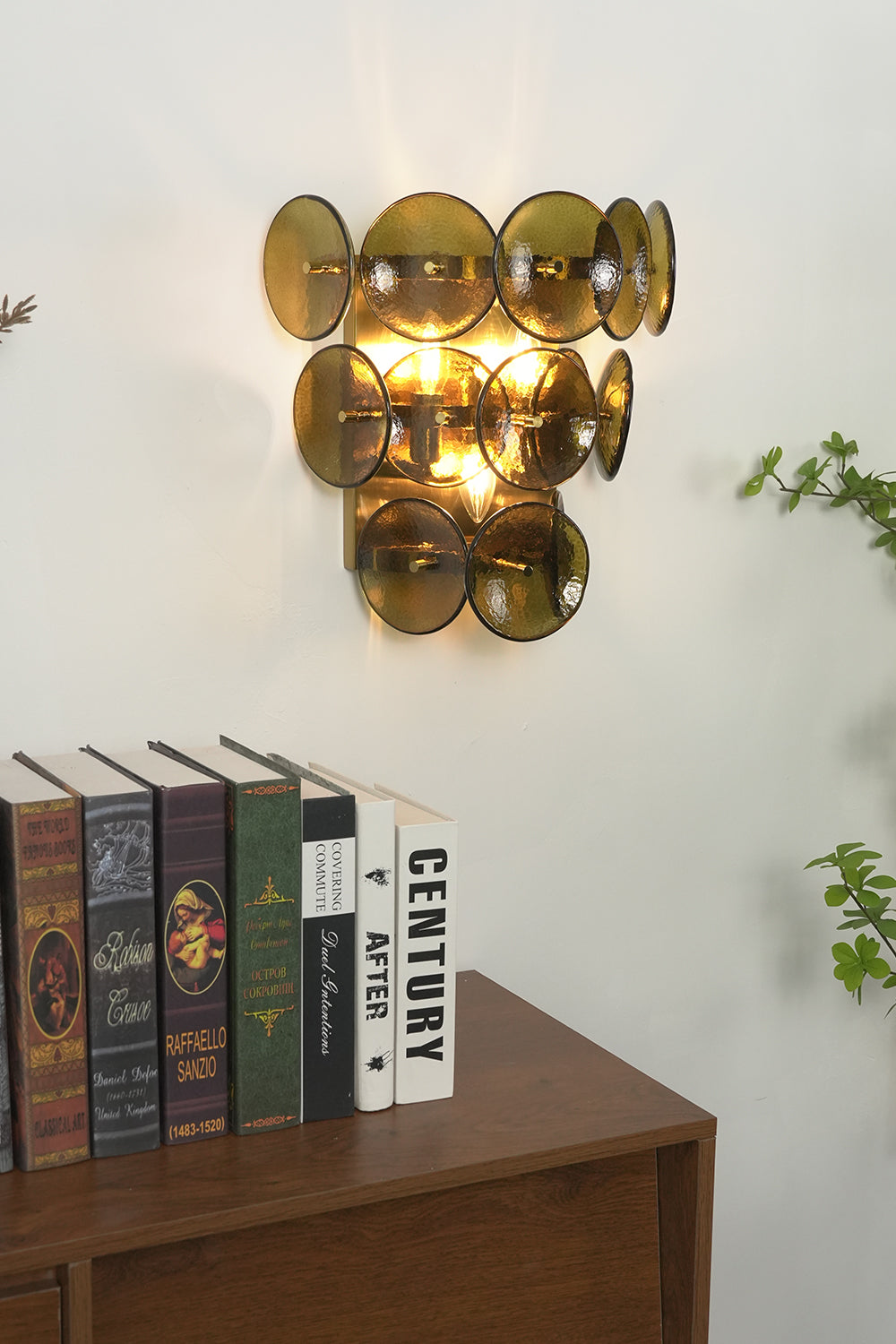 Close-up of lit olive green glass disc lamp | Metal, Glass | Positioned above stacked vintage books | Samu Lamp