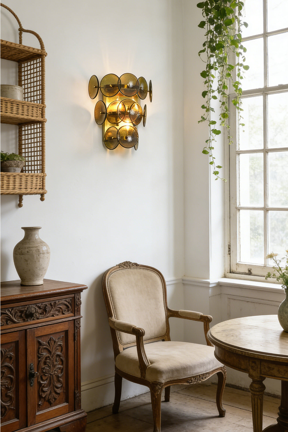 Lit tiered olive green glass wall lamp | Metal, Glass | Installed in a sunlit room with wicker furniture | Samu Lamp