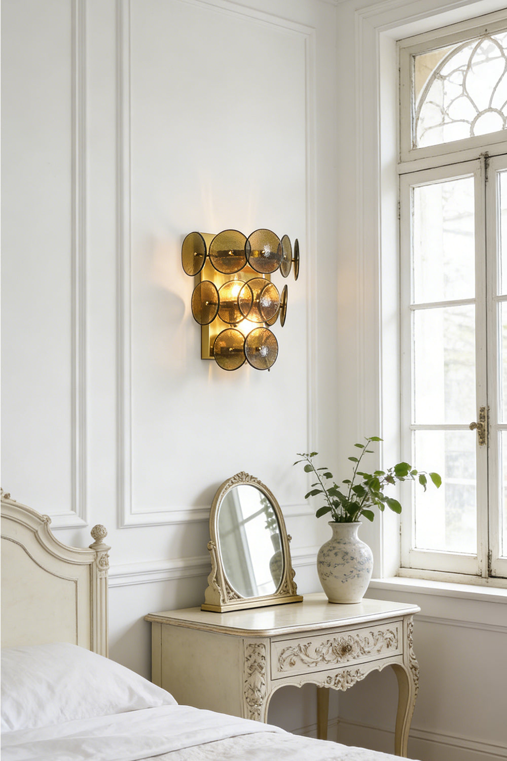 Lit olive green glass wall sconce | Metal, Glass | Installed in a classic bedroom near a white dresser and mirror | Samu Lamp