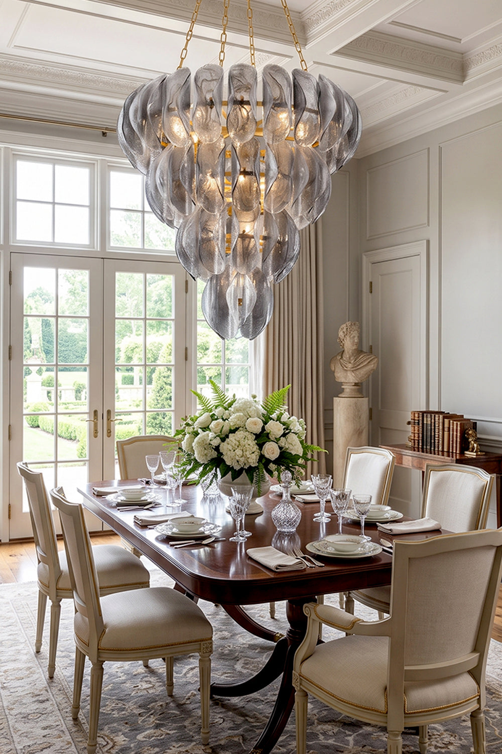 Ondine Cascading Leaf Glass Chandelier | Textured Smoked Glass and Gold Metal | Positioned over a classic wooden dining table surrounded by cream chairs near a window to the garden | Samu Lamp