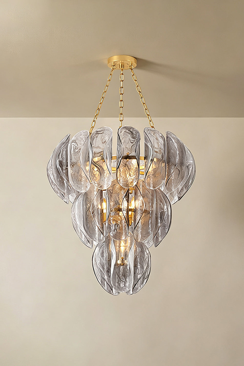 Ondine Cascading Leaf Glass Chandelier | Textured Smoked Glass and Gold Metal | Displayed hanging from a plain plaster ceiling casting soft warm ambient illumination in a room | Samu Lamp