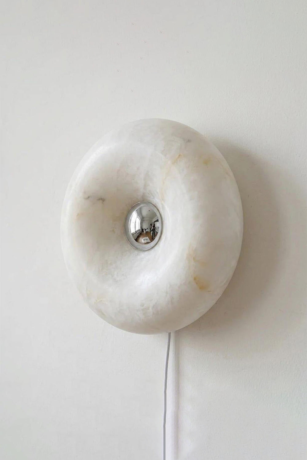 Ondine Ring Alabaster Wall Sconce featuring natural alabaster with a chrome bulb accent on a white wall.