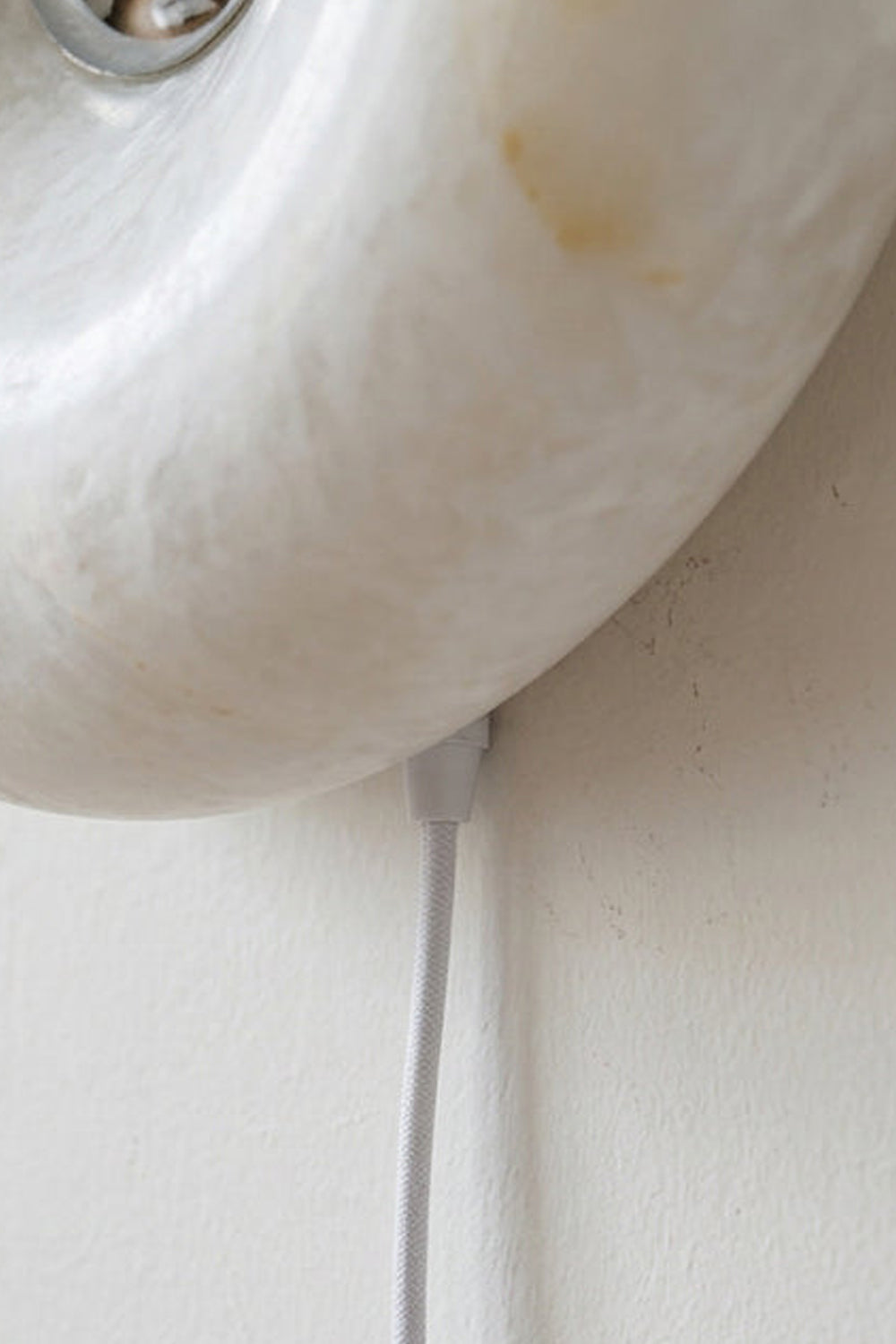 Ondine Ring Alabaster Wall Sconce with a close-up of its alabaster texture and power cable.