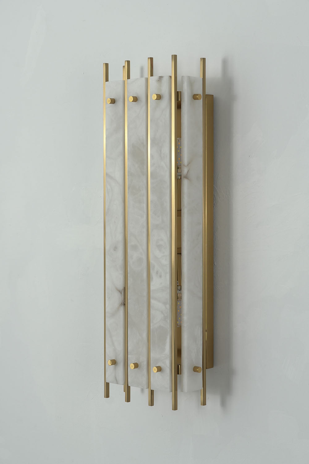 Ondrelle Bar Wall Sconce | Natural Stone and Brass | Angled three-quarter perspective on grey wall, unlit | Samu Lamp