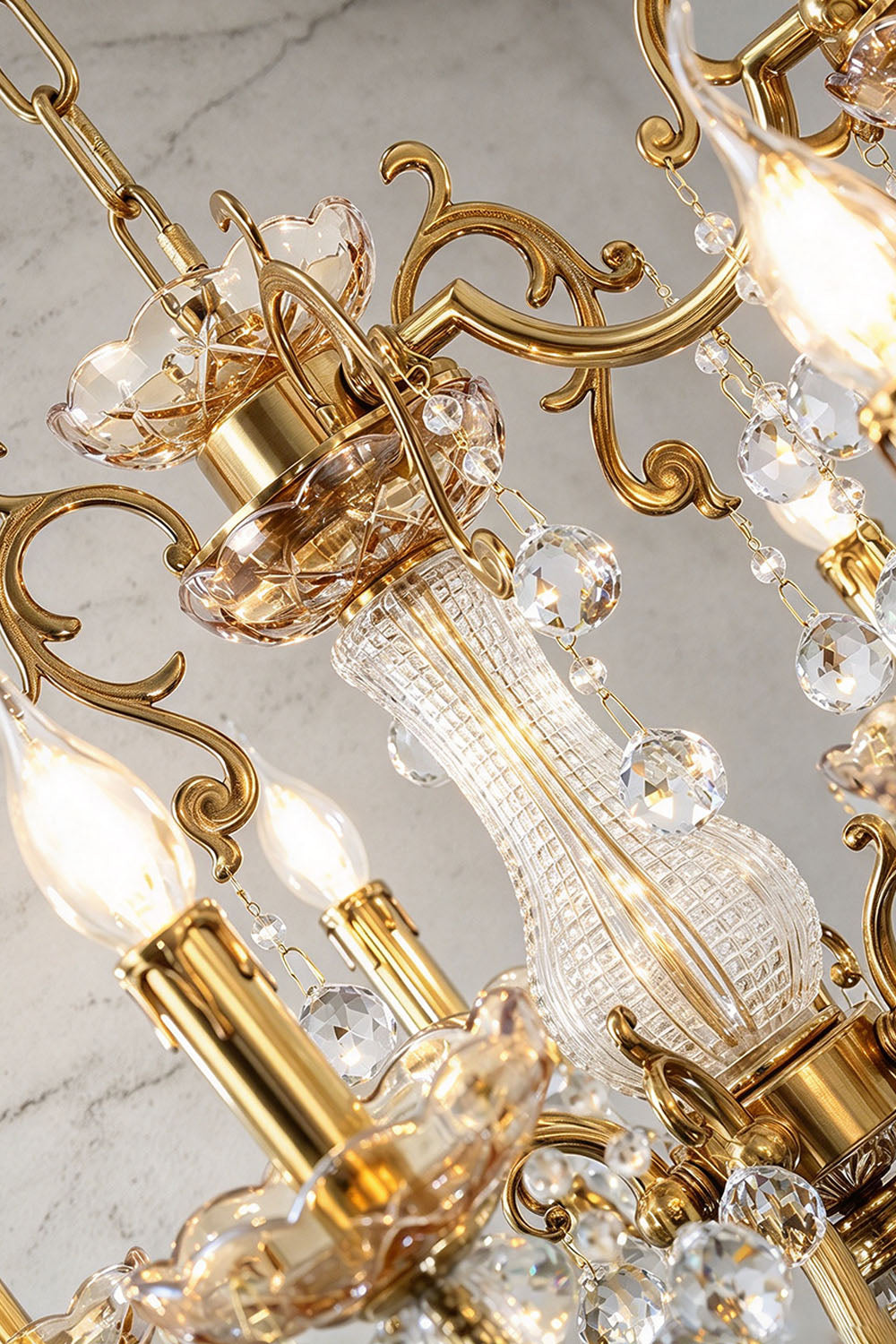 Orbessan Brass Crystal Oval Candle Chandelier | Cut Crystal and Brass | Angled detail shot of the central brass structure and candle sleeves | Samu Lamp