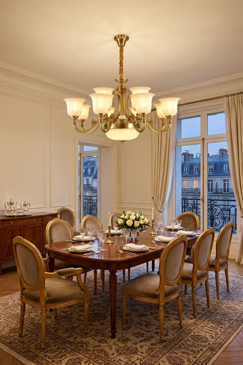 Ormond Fluted Bell Brass Chandelier illuminating an elegant dining room with wooden table and ornate chairs.