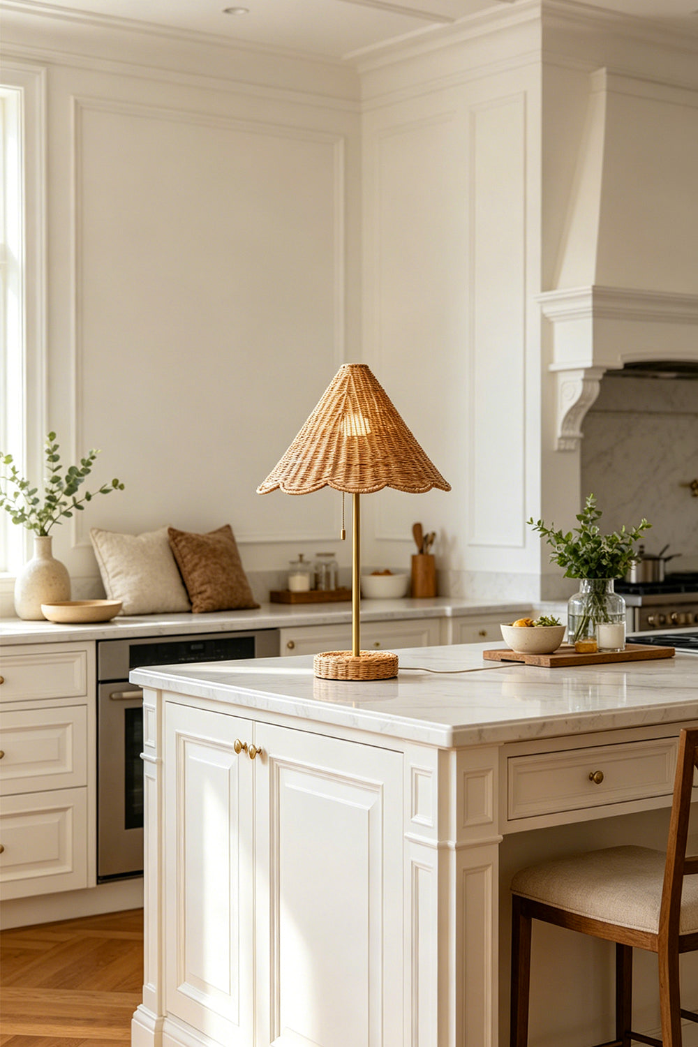 Osrilla Scalloped Rattan Table Lamp | Rattan, Brass | Serving as an elegant decorative light centerpiece on a pristine white marble kitchen island counter under natural daylight | Samu Lamp