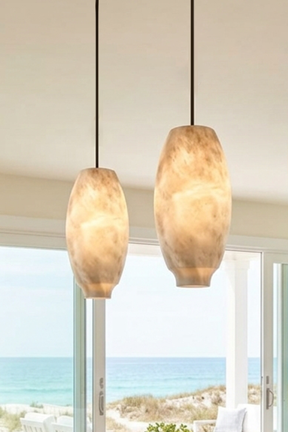 Ottilie Barrel Alabaster Pendant Light | Natural Alabaster and Metal | Pair of tall barrel alabaster pendants near floor-to-ceiling ocean view windows | Samu Lamp