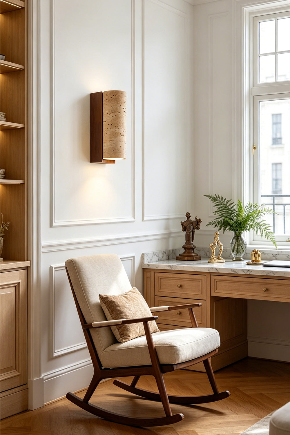 Outcrop Beige Travertine Wall Sconce | Travertine, Metal | Staged gracefully on a living room wall, casting a soft warm light above a white rocking chair with a wooden desk nearby | Samu Lamp