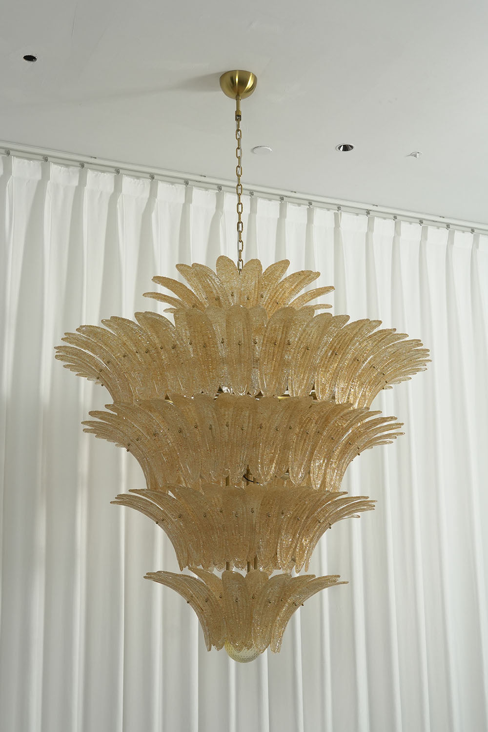 Palmonde Palm Leaf Chandelier | Amber Glass and Brass | Full hanging view unlit against white drape background | Samu Lamp