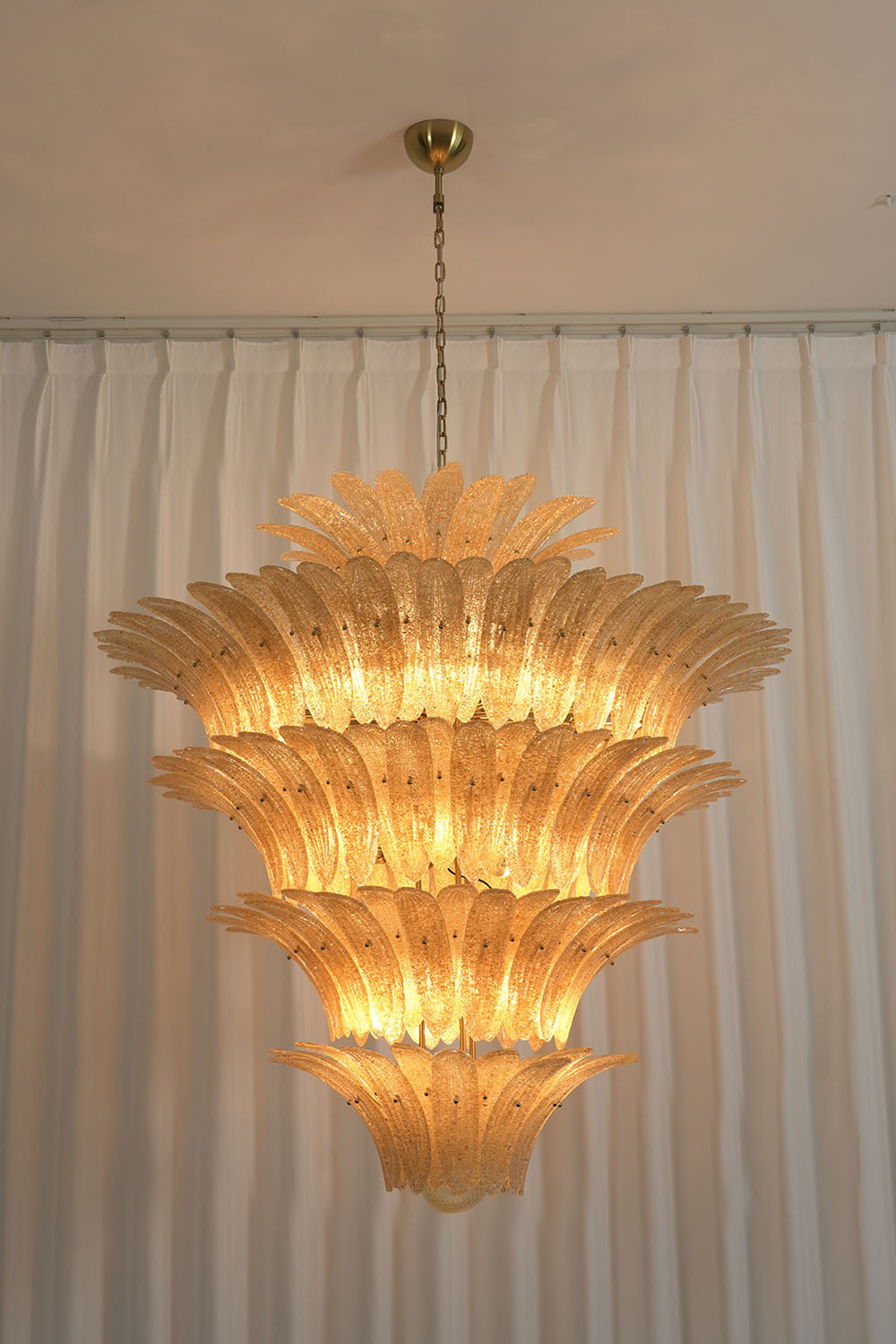 Palmonde Palm Leaf Chandelier | Amber Glass and Brass | Front illuminated view against white curtain backdrop | Samu Lamp