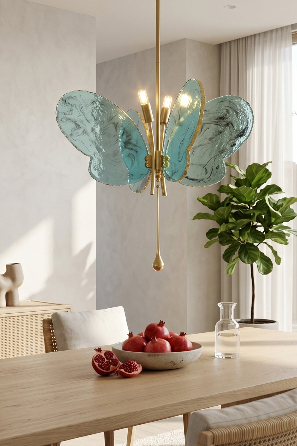 Papillon Glass Butterfly Pendant Lamp | Glass, Metal | Closer view of the glowing blue butterfly fixture over a wooden dining setup decorated with a bowl of red apples | Samu Lamp