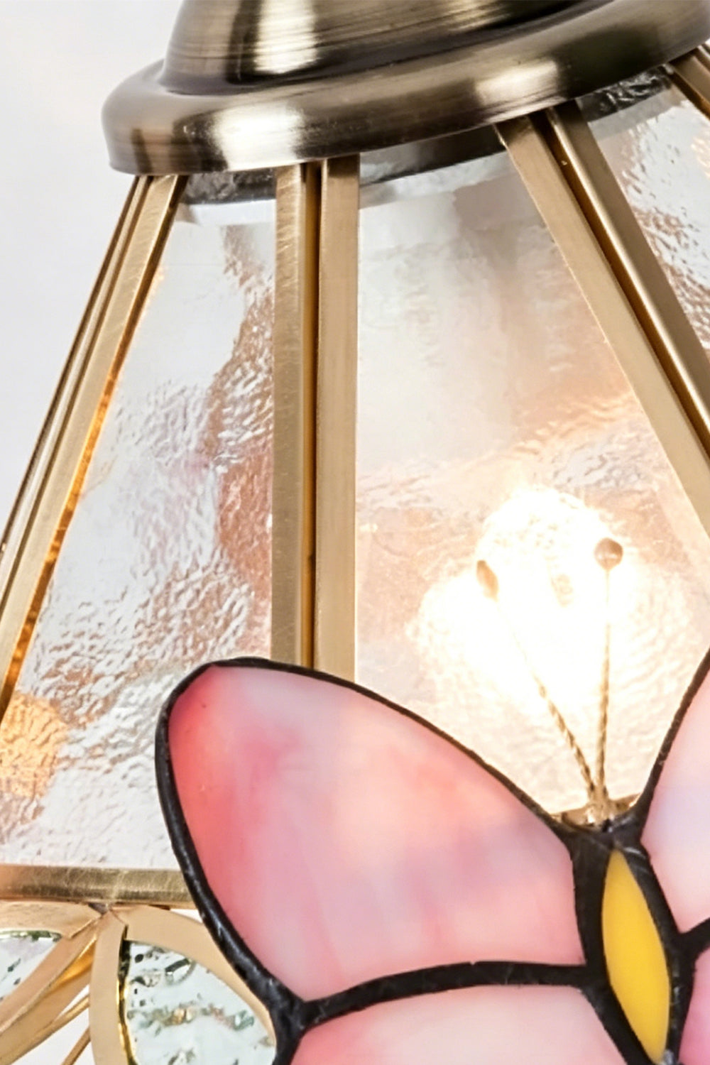 Papillon Heirloom Stained Table Lamp | Wood, Glass, Metal | Macro close-up of the lit textured glass panel, brass framework, and a pink butterfly wing | Detail shot | Samu Lamp