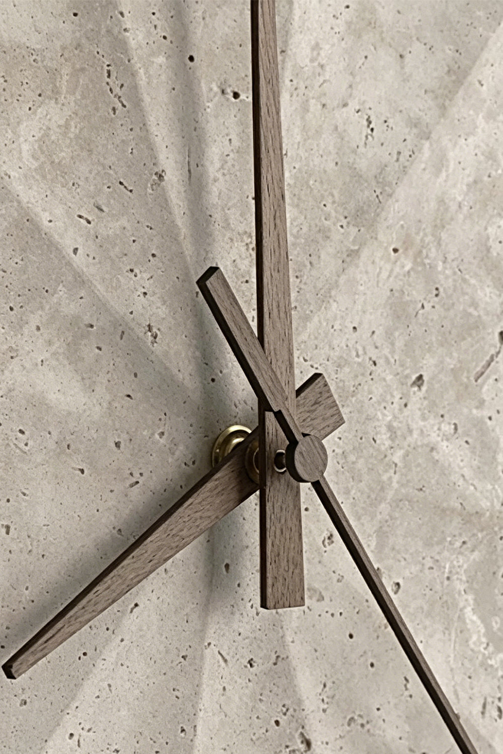 Petra Compass Travertine Backlit Wall Lamp | Travertine, Iron | Extreme macro close-up of the dark iron compass-like hands fixed onto the textured travertine surface | Detail shot | Samu Lamp