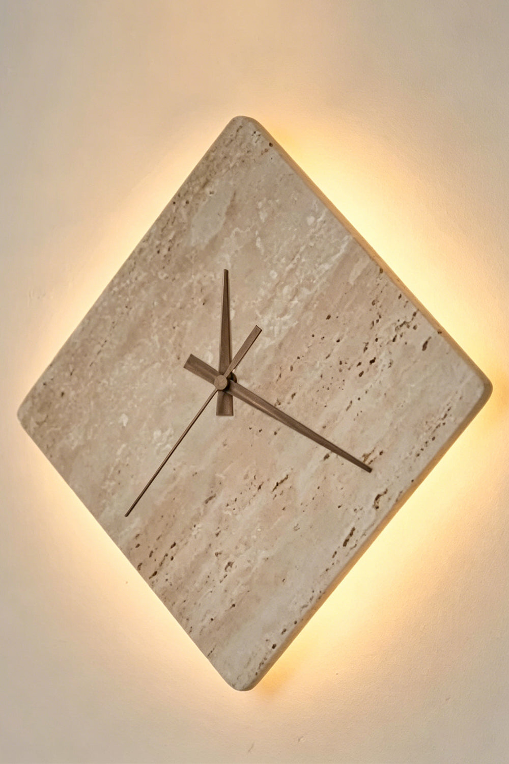 Petra Compass Travertine Backlit Wall Lamp | Travertine, Iron | Fully lit stone wall lamp radiating a warm, soft backlight halo from behind the diamond edges | Isolated lit shot | Samu Lamp