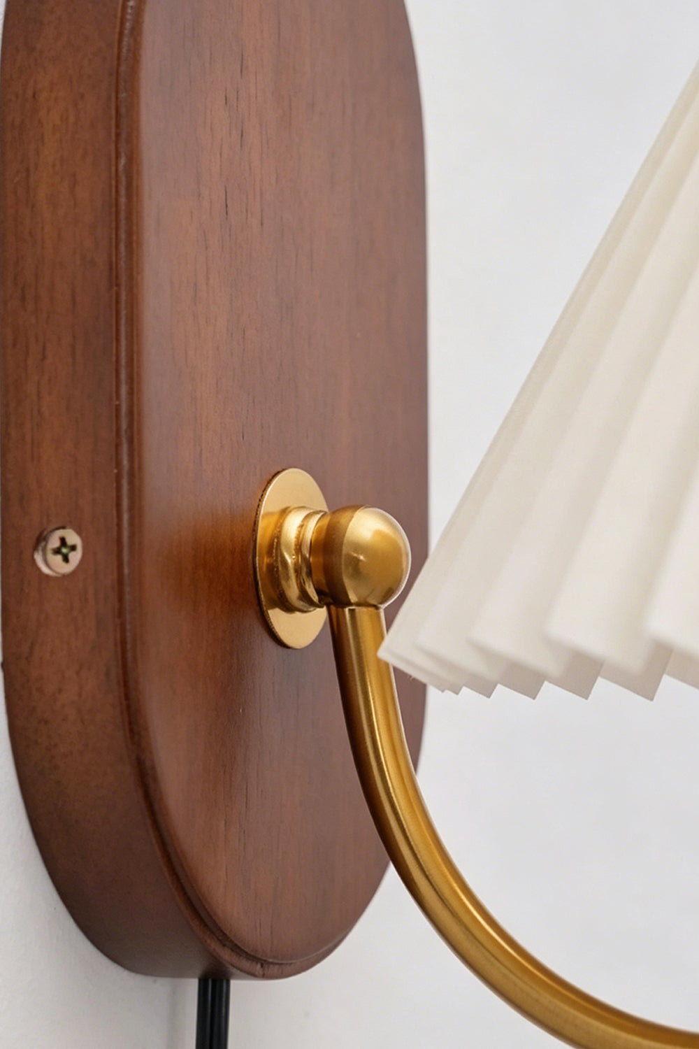 Pleated Fabric Wall Lamp | Fabric, Metal, Wood | Close-up focus on the gold brass swivel joint connected to the smooth polished oval wooden backplate | Detail shot | Samu Lamp