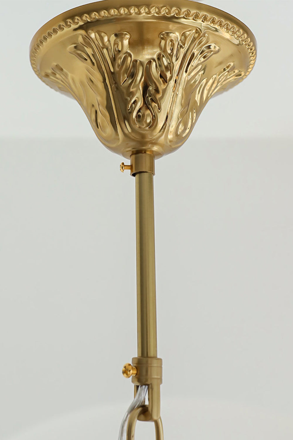 Pluma Frosted Glass Feather Chandelier | Glass, Metal | Close-up shot highlighting the ornate decorative carvings on the polished gold brass ceiling canopy and mounting rod | Detail shot | Samu Lamp