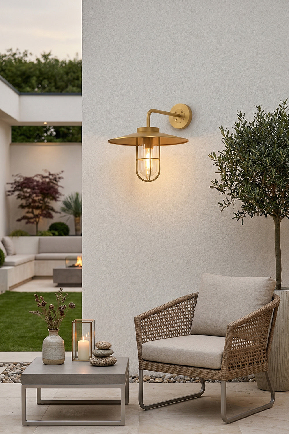 Brass Portree wall lamp installed on an outdoor patio wall | Brass, Glass | Outdoor garden scene with lounge furniture | Samu Lamp