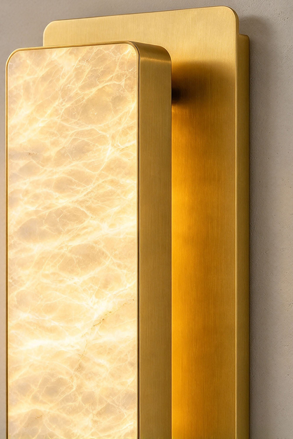 Quadrelle Wall Sconce | Alabaster and Brass | Close-up side angle of brass backplate and illuminated shade | Samu Lamp