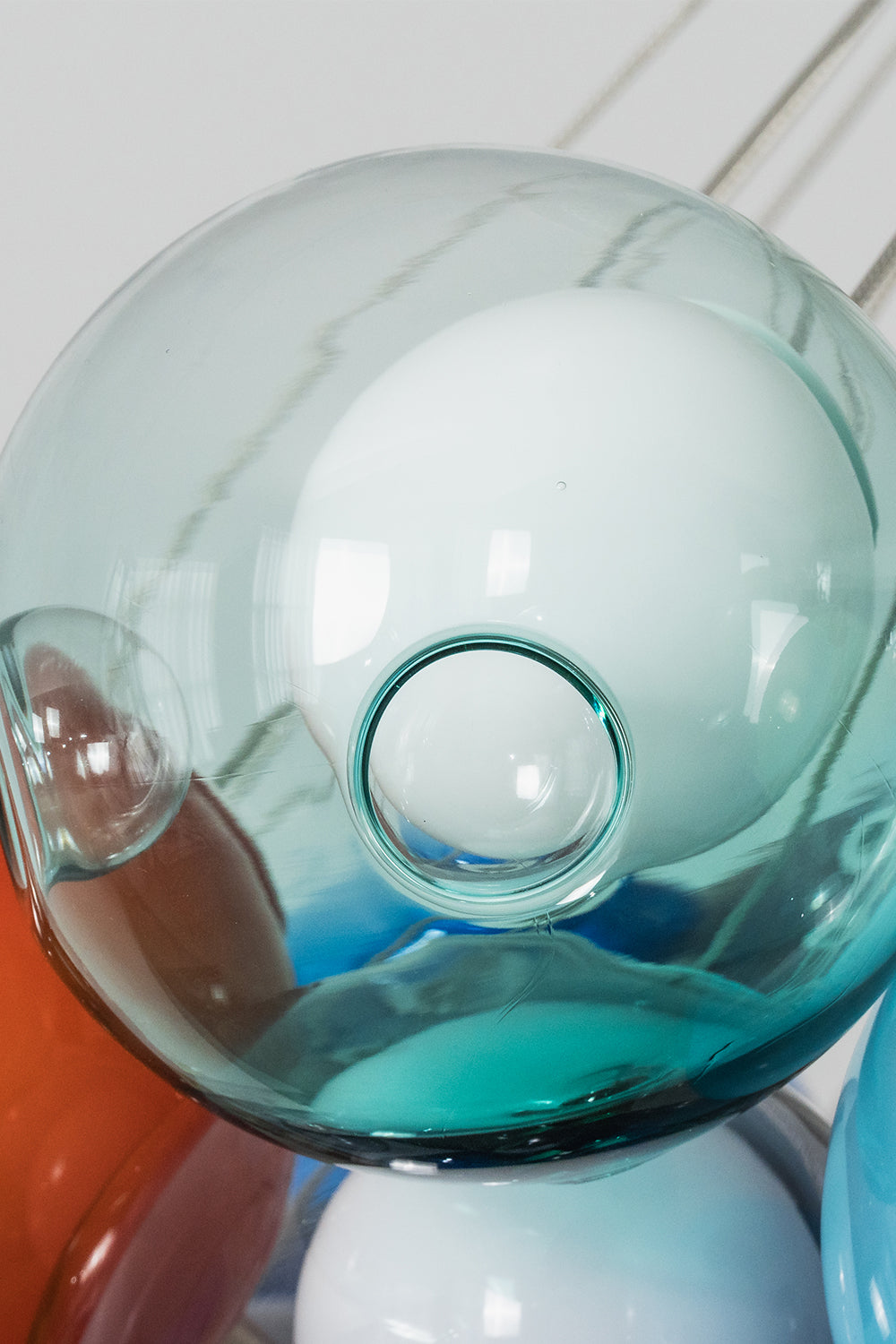 Rainbow Glass Bubble Cluster Chandelier | Glass, Metal | Close-up focus on a light mint blue glass bubble showing the glass loops and wiring top connection | Detail shot | Samu Lamp