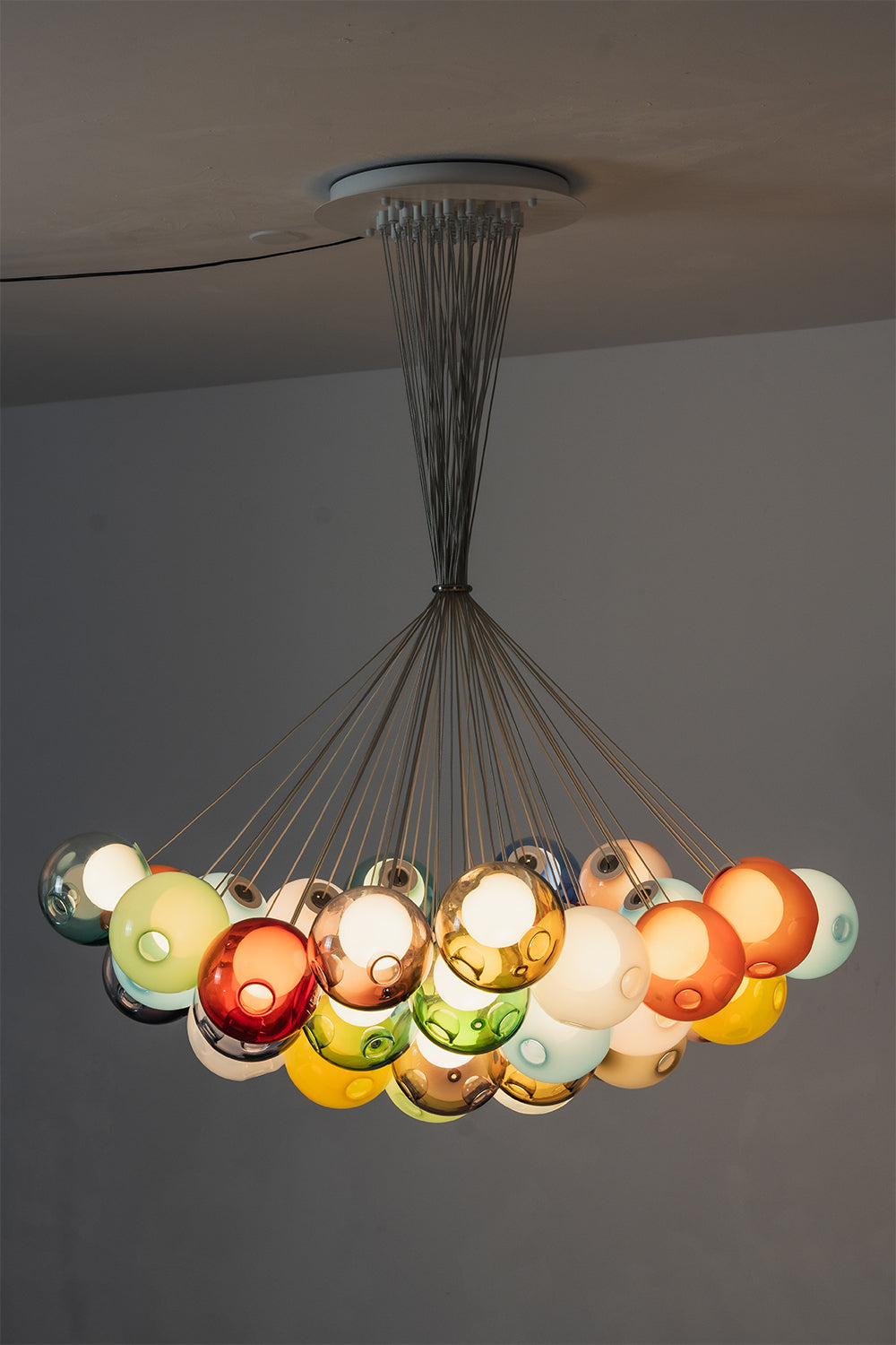 Rainbow Glass Bubble Cluster Chandelier | Glass, Metal | Side profile view of the wide crescent cluster arrangement fully illuminated against a neutral studio backdrop | Samu Lamp