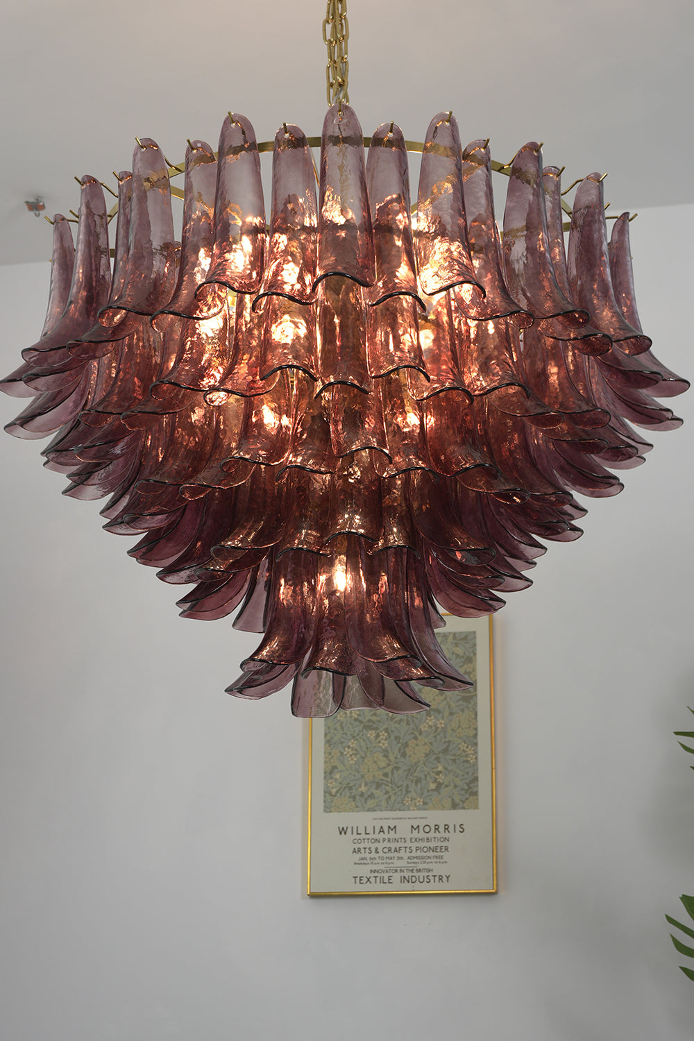 Regal Purple Cascade Chandelier | Glass, Metal | Front view of the lit chandelier against a plain wall, highlighting the warm glow | Detail shot | Samu Lamp