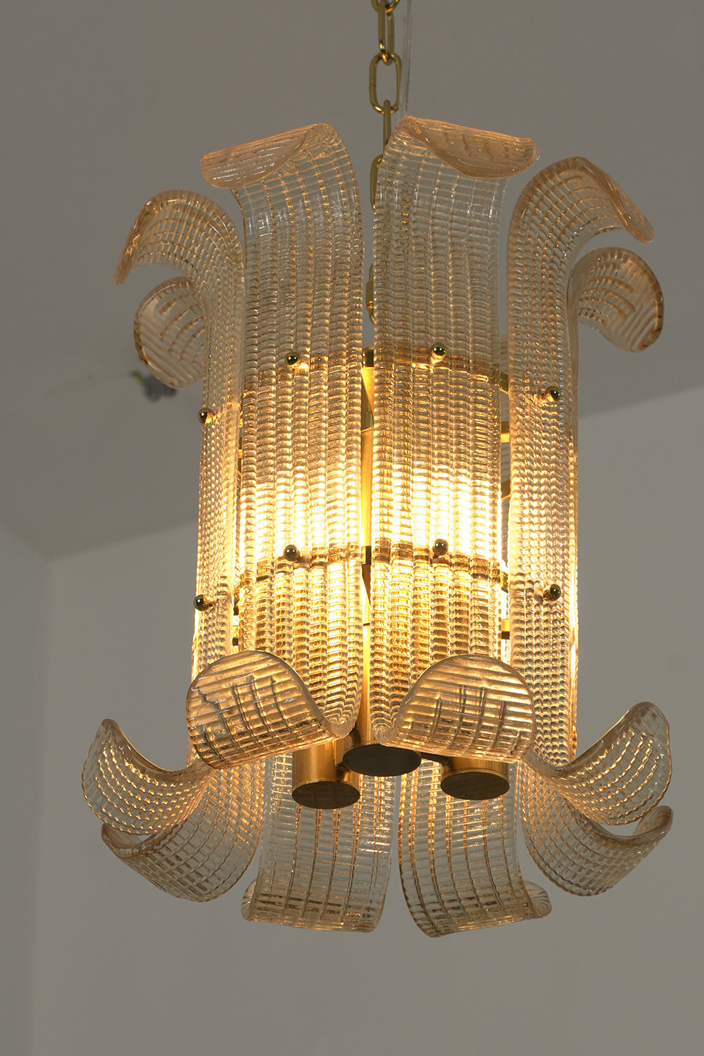 Internal brass frame and curved glass scroll panels | Metal | Glass | Side profile view showing the chandelier's intricate construction | Samu Lamp