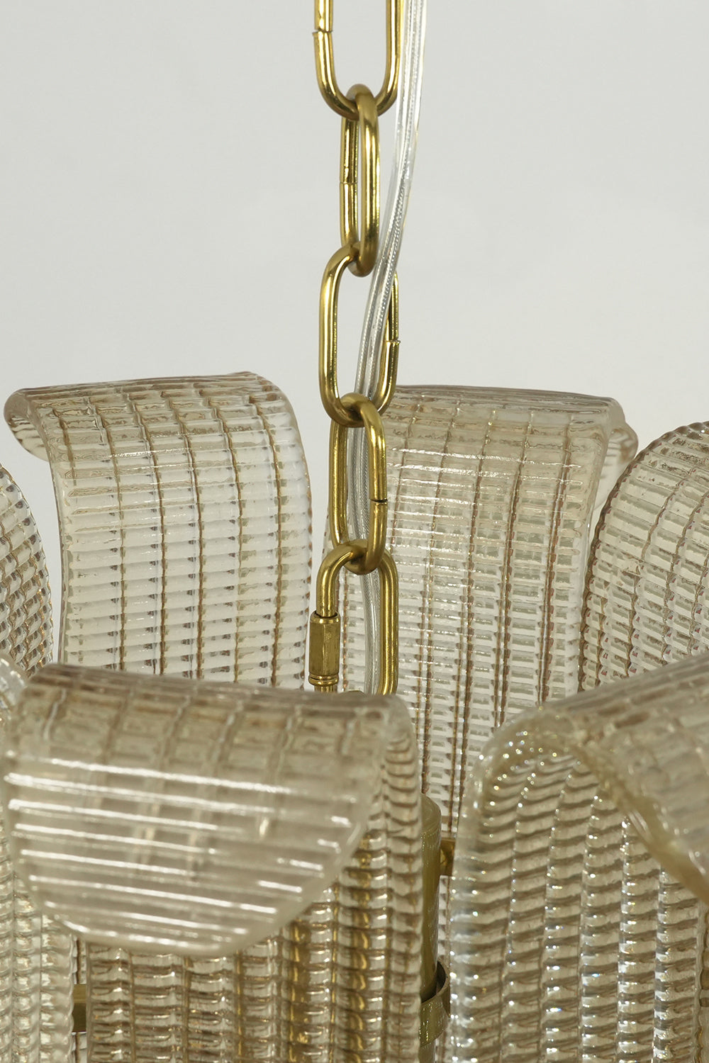 Top section of the ribbed glass scroll chandelier | Metal | Glass | Close-up of the gold chain and glass panel attachment | Samu Lamp
