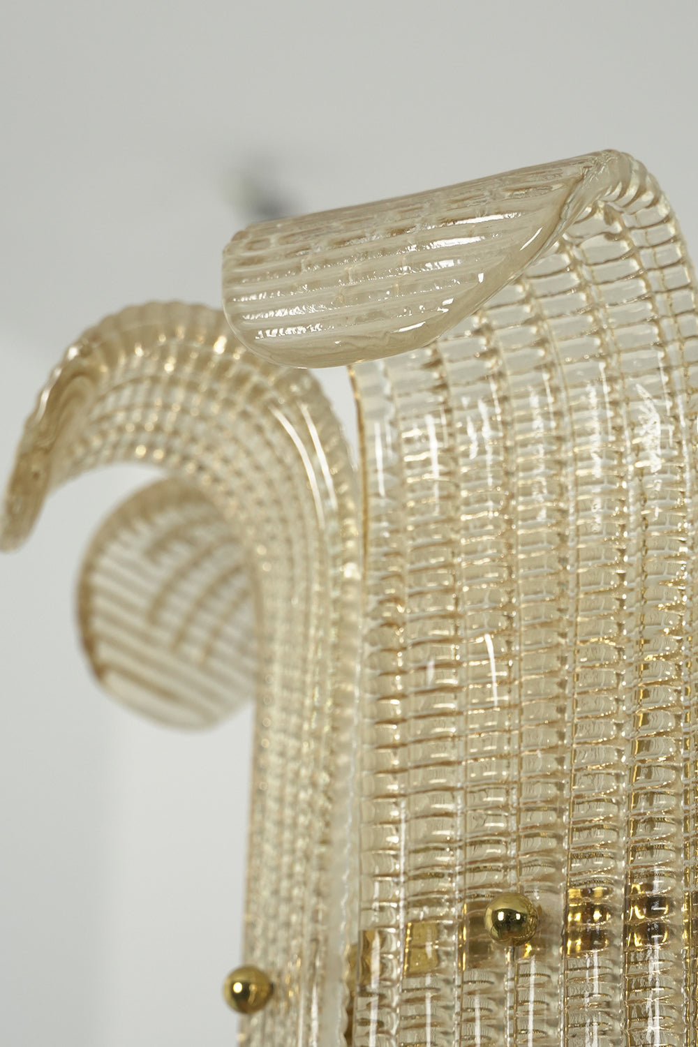 Close-up detail view of the ribbed glass texture | Glass | Showing the clarity and distinct scroll shape of the wall lamp | Samu Lamp