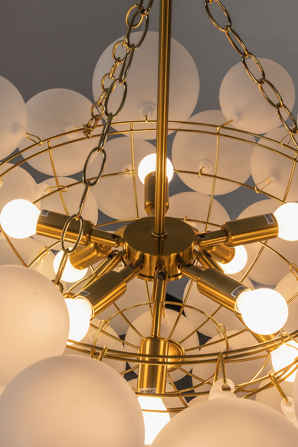 Romilly Frosted Globe Cluster Chandelier | Frosted Glass and Brass | Close-up view highlighting the inner brass frame structure and illuminated bulbs | Samu Lamp