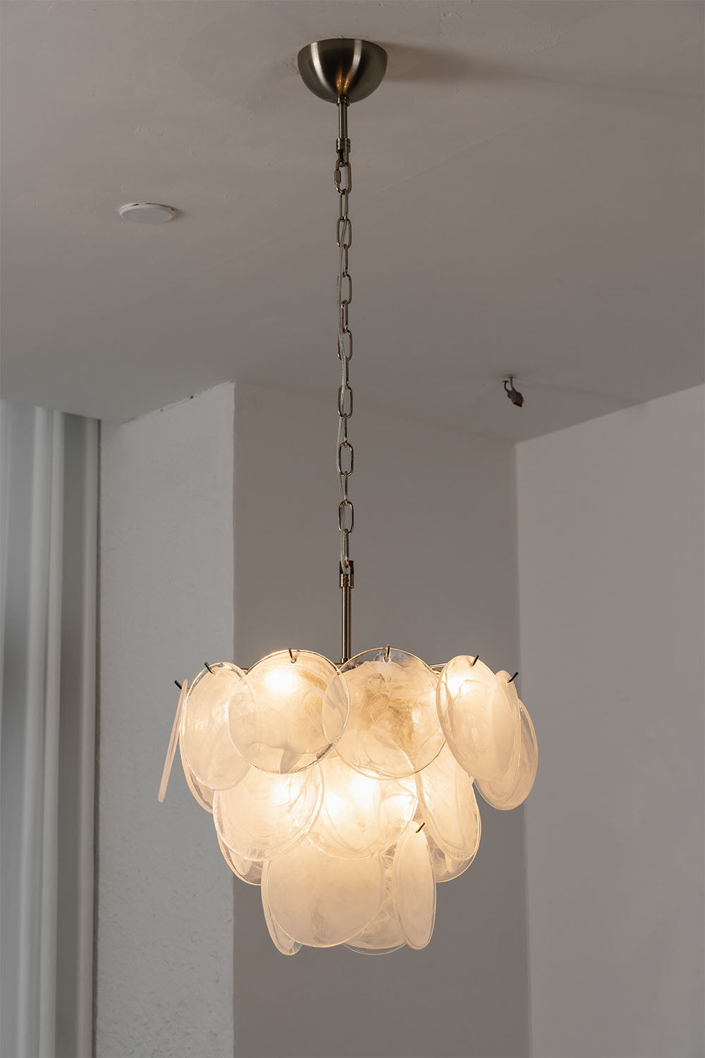 Romilly Layered Glass Disc Chandelier hanging from a ceiling with soft illumination and layered glass design.