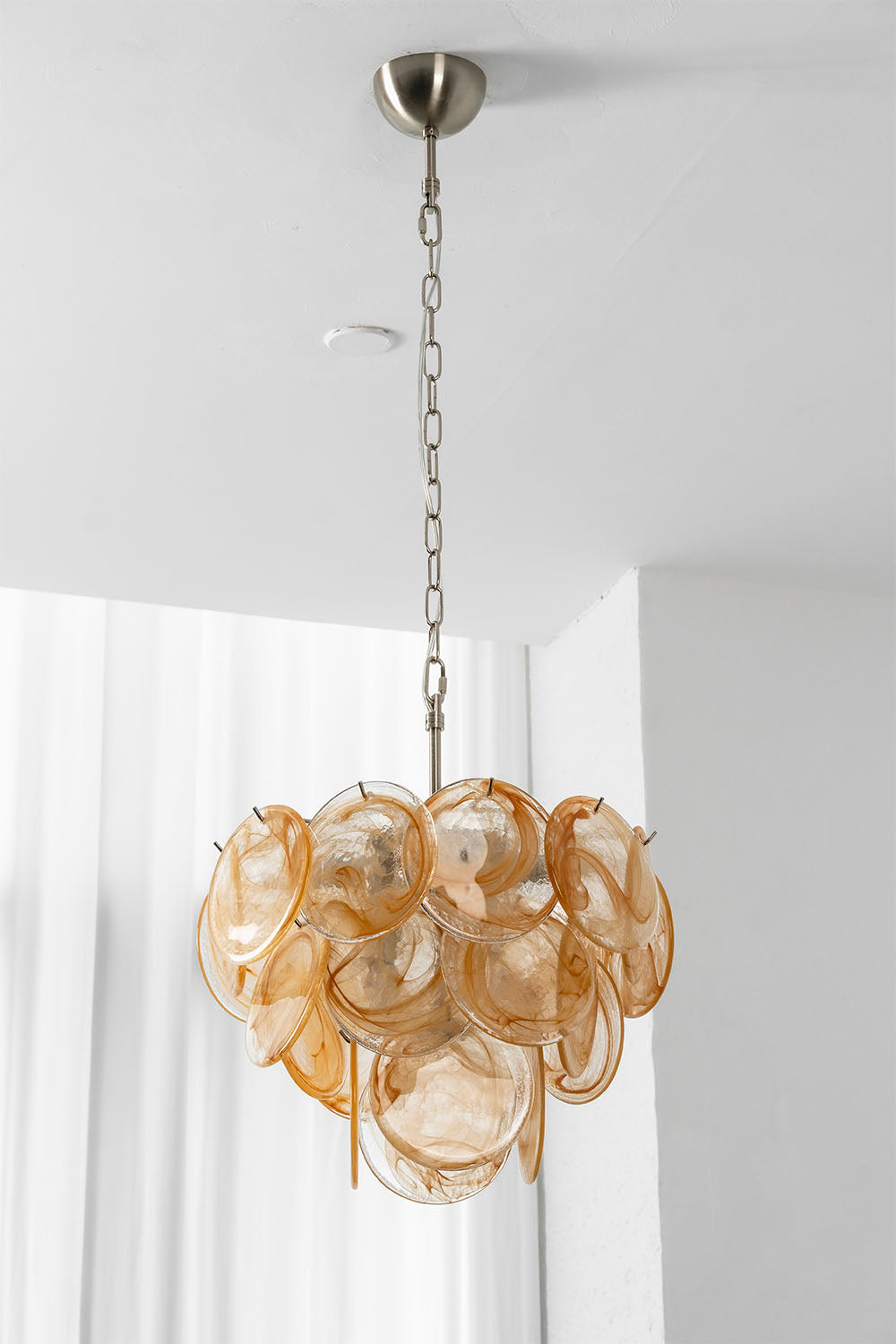 Romilly Layered Glass Disc Chandelier featuring layered glass discs in warm tones, suspended from a sleek metal chain.