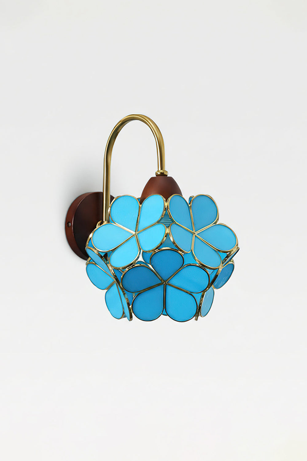 Rosalind Petal Glass Botanical Wall Lamp | Glass, Metal, Wood | Isolated lit product view of the vibrant blue glass petal variant glowing intensely against a white background | Samu Lamp