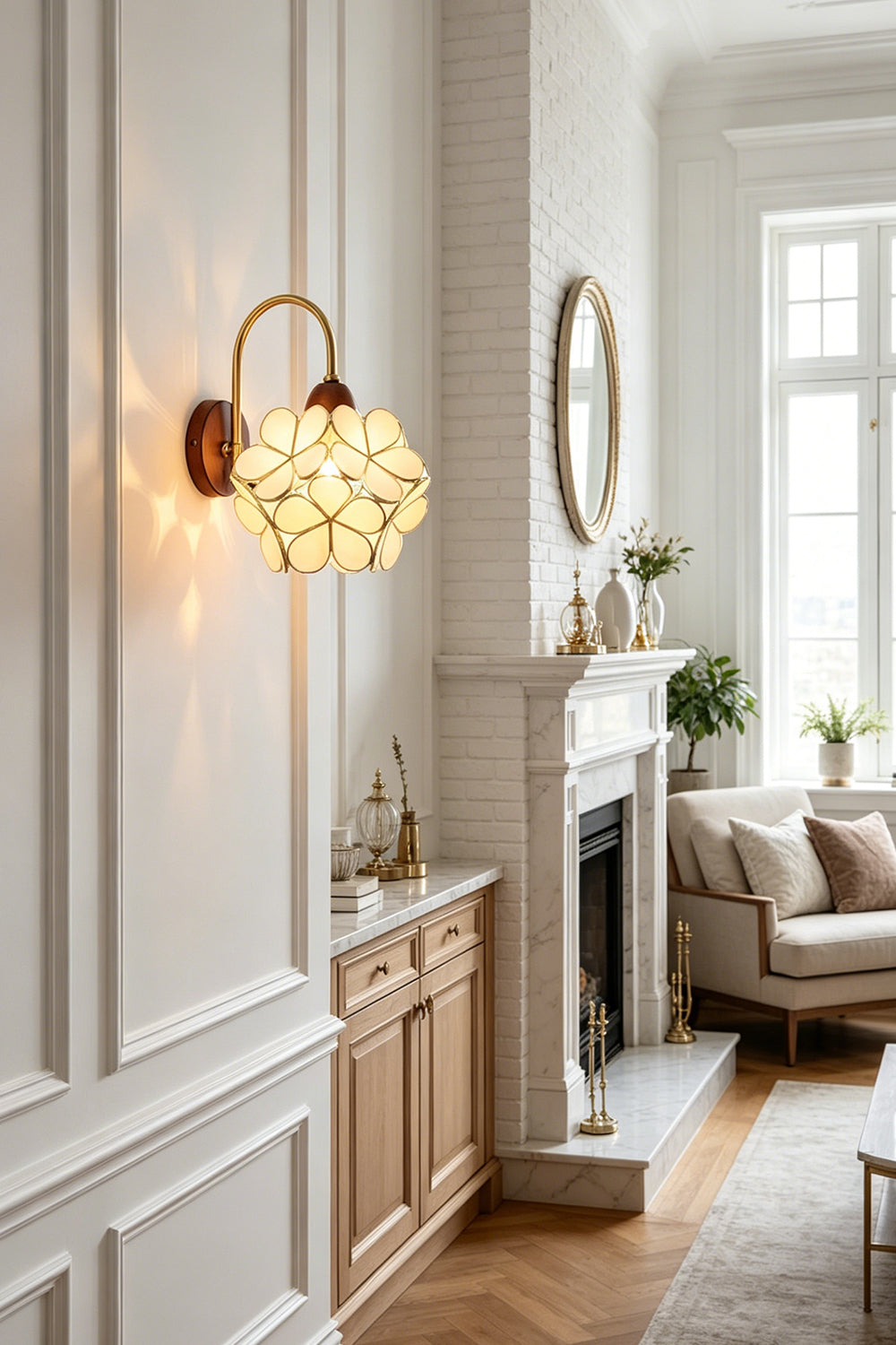Rosalind Petal Glass Botanical Wall Lamp | Glass, Metal, Wood | Close-up view of the glowing floral sconce throwing soft warm light on a white wall near a fireplace mantel | Samu Lamp