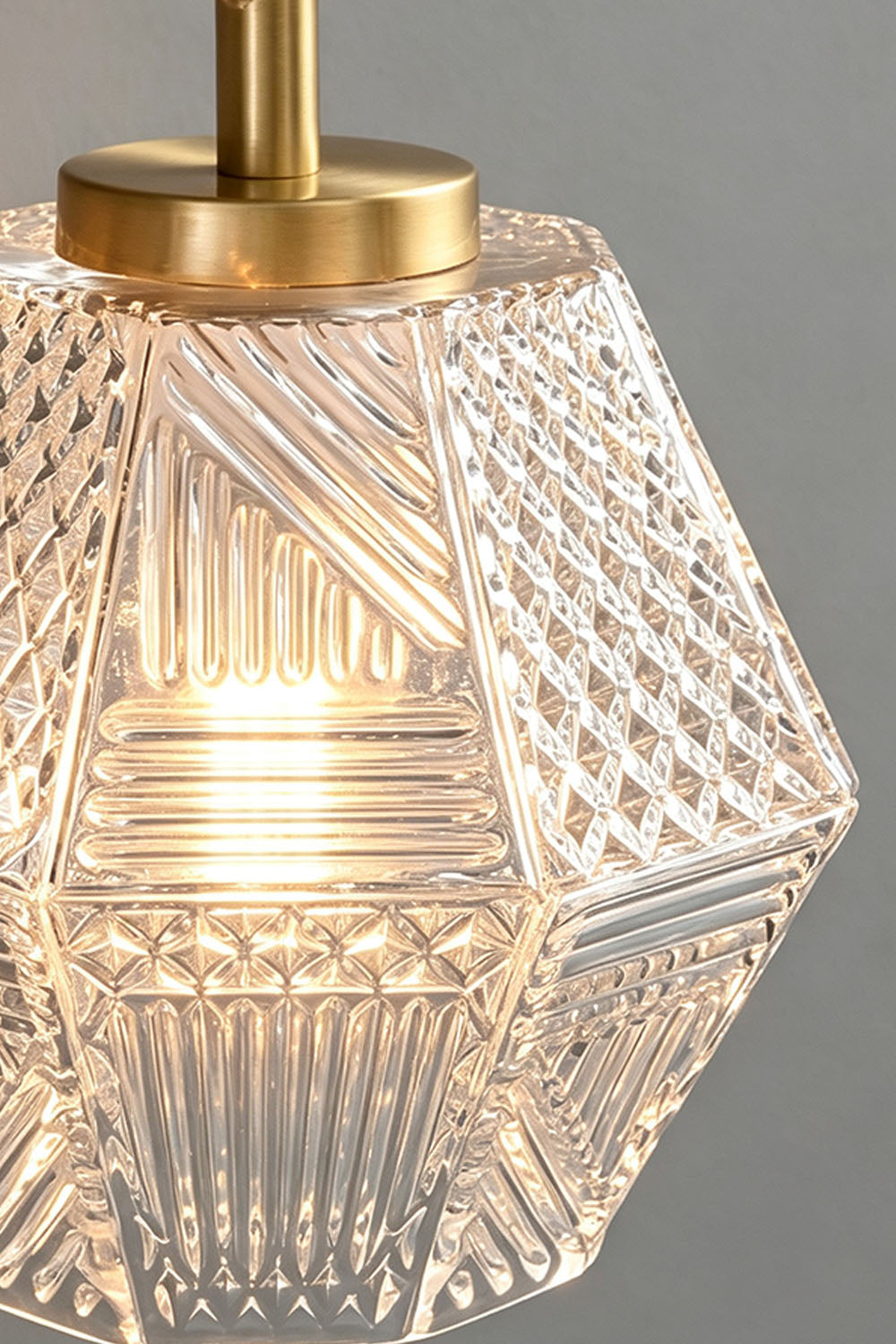 Rosamund Faceted Glass Wall Sconce | Faceted Glass and Brass | Close-up detail of the illuminated clear faceted glass shade | Samu Lamp