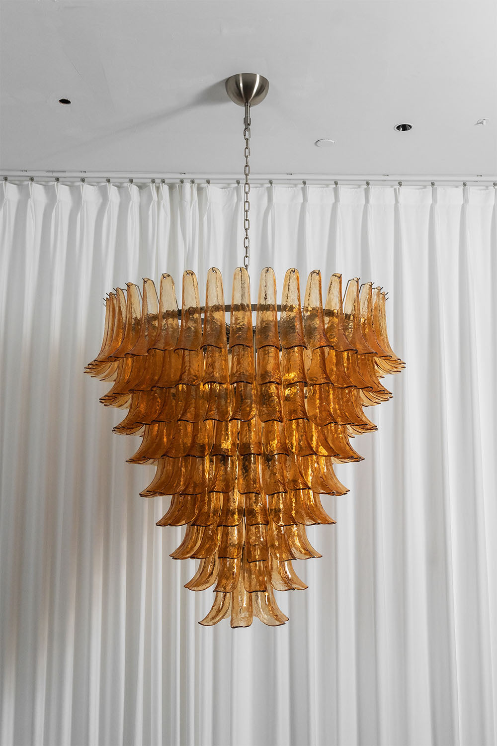 Rouveline Rippled Amber Glass Cone Chandelier | Rippled Amber Glass and Metal | Full vertical product view illuminated against white background drapes | Samu Lamp
