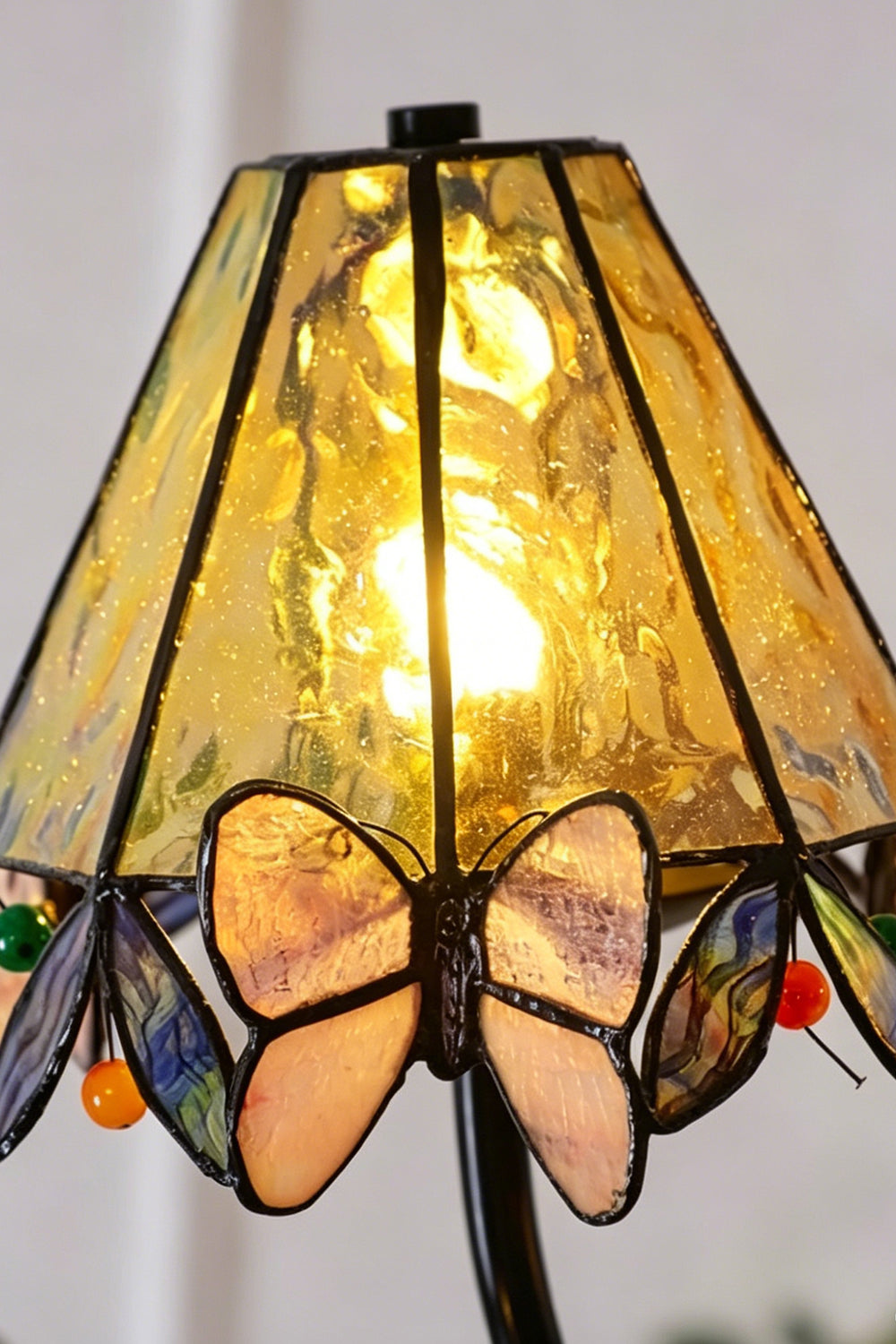 Seraphina Stained Glass Chandelier | Glass, Metal | Extreme close-up of a single lit conical Tiffany shade radiating a warm yellow glow through the textured glass | Detail shot | Samu Lamp
