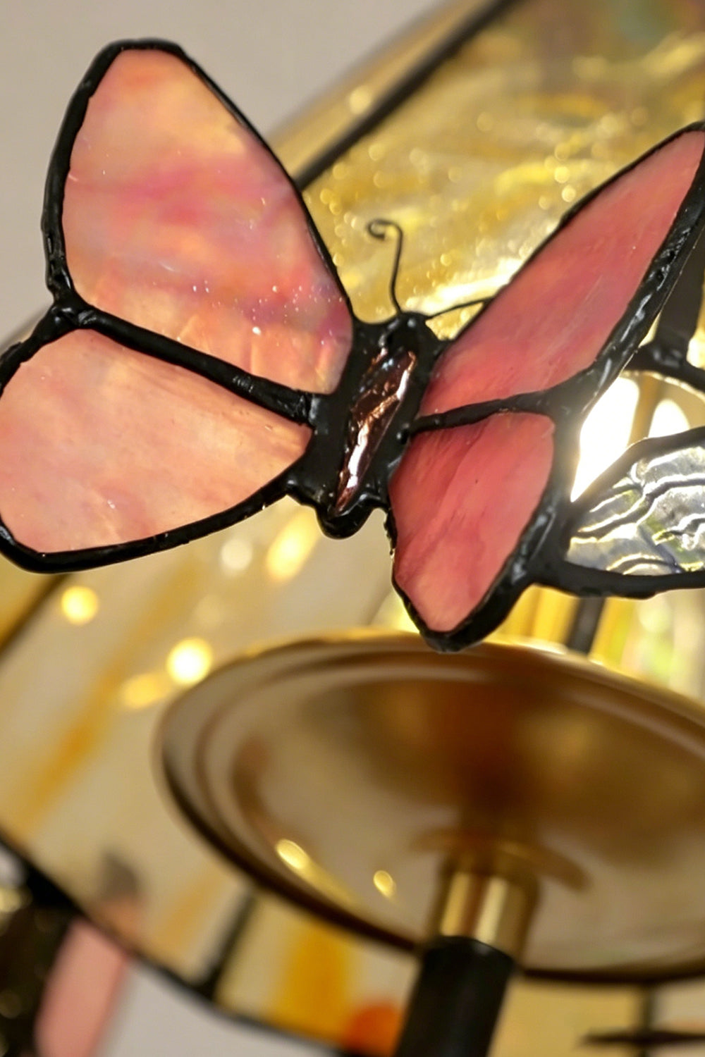 Seraphina Stained Glass Chandelier | Glass, Metal | Macro view of a translucent pink stained glass butterfly embellishment attached to the shade's rim | Detail shot | Samu Lamp