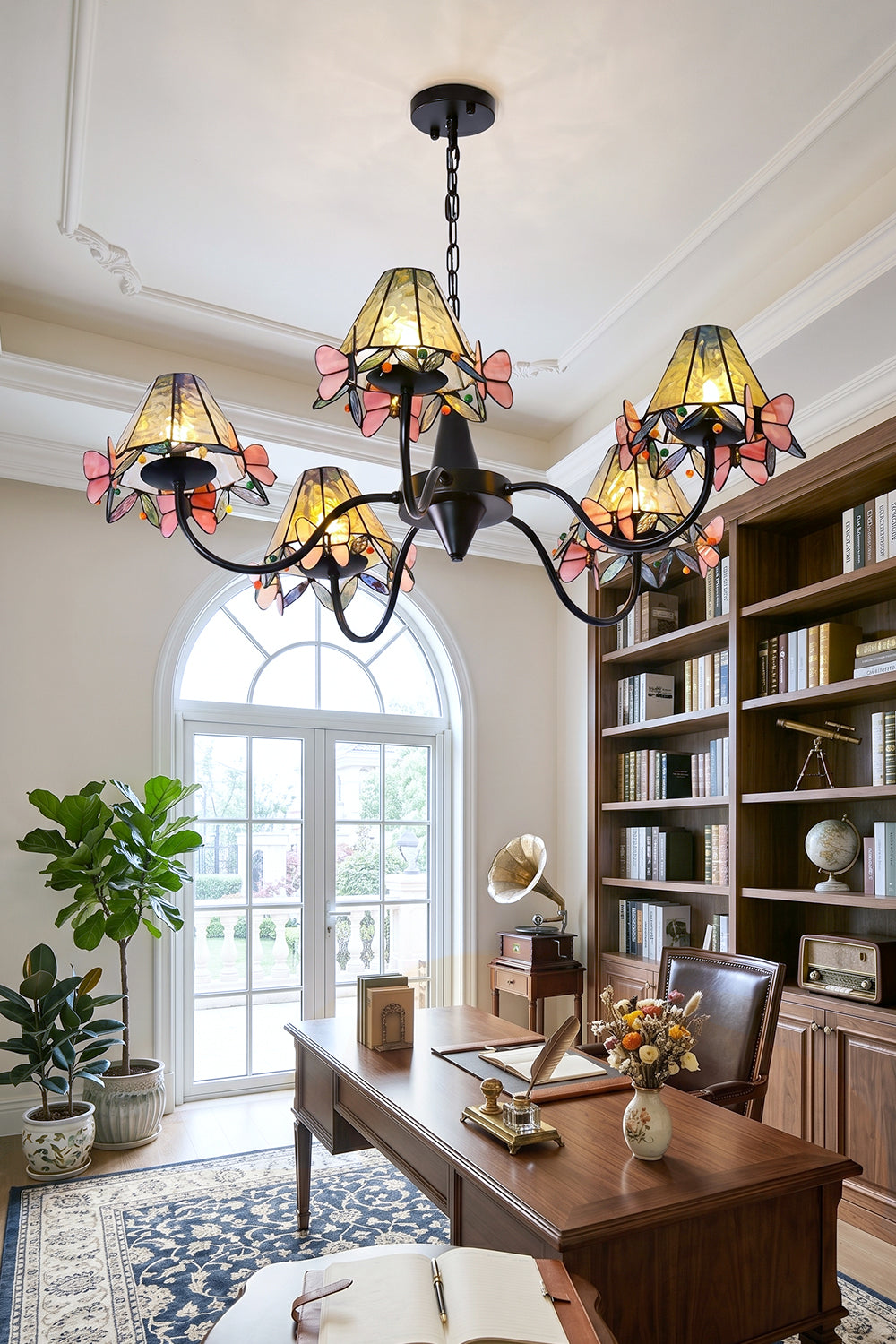 Seraphina Stained Glass Chandelier | Glass, Metal | Hanging in a modern office setup beside built-in bookshelves and facing an arched window | Samu Lamp