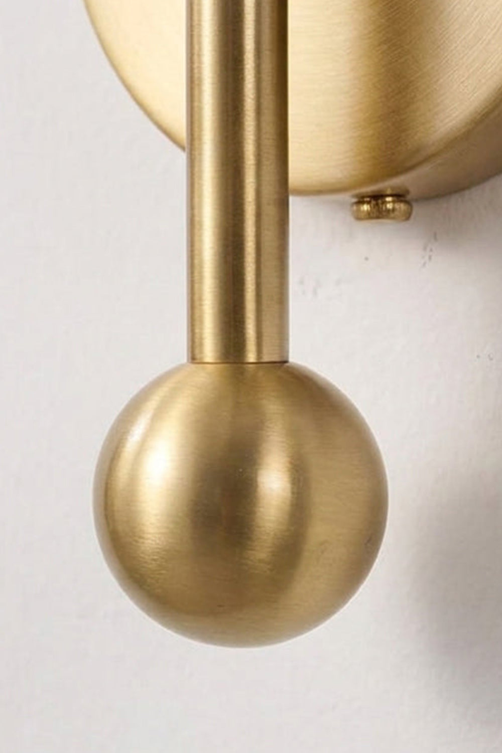 Detail of the Seraphine Alabaster Globe Wall Sconce with a sleek gold tone finish and spherical finial.