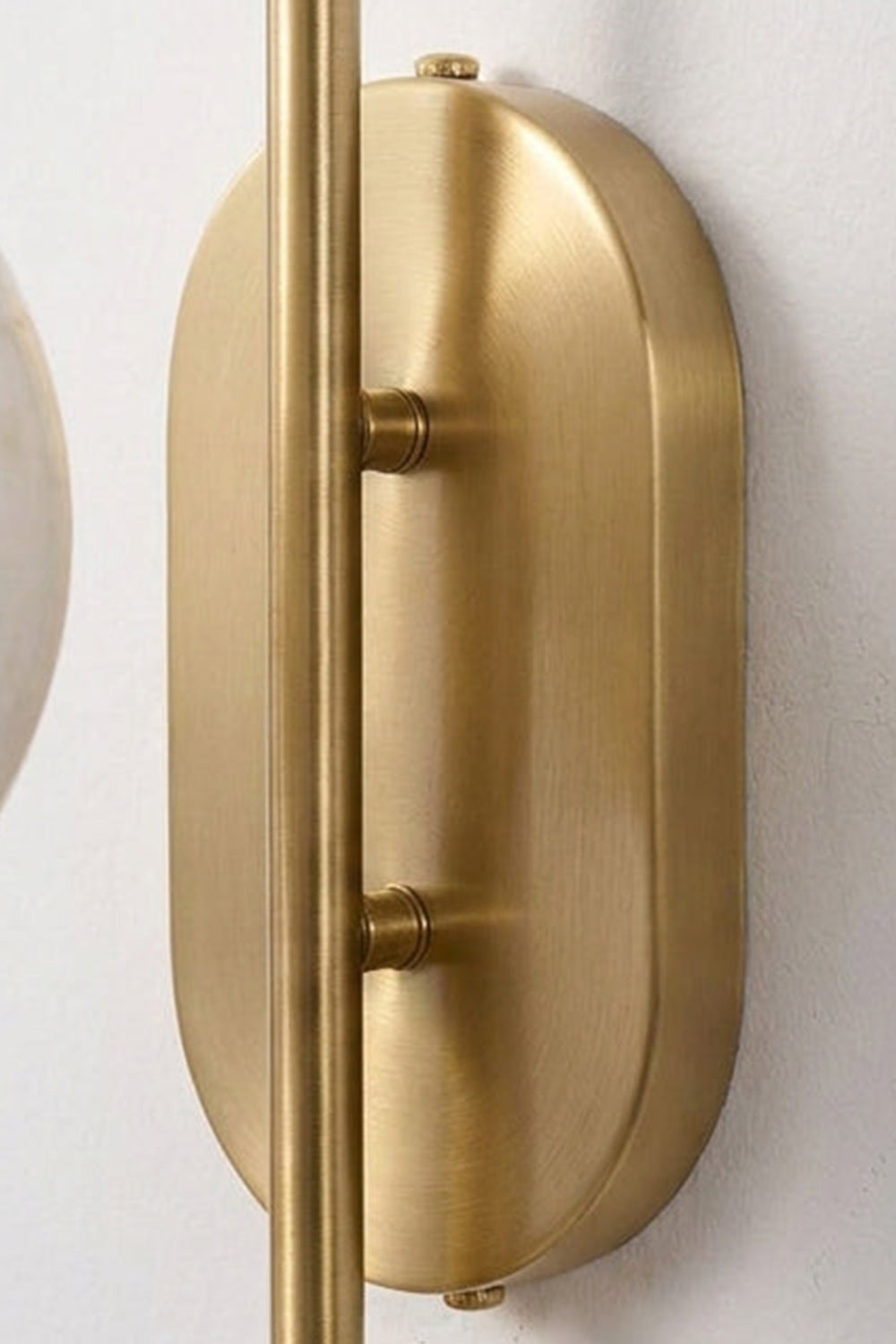Close-up of the slim oval backplate of the Seraphine Alabaster Globe Wall Sconce in gold-toned finish.